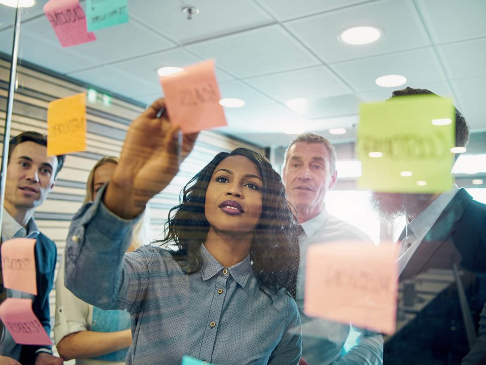 Grupo de pessoas em reunião discutem ideias utilizando cartões e post-it